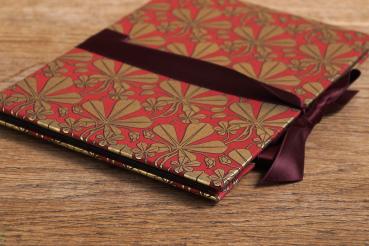 Handmade leporello with red cover paper and golden maple leaves, red ribbon for tying